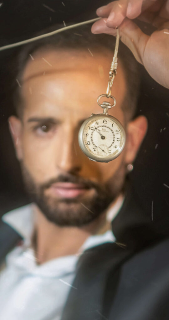 Paolo calabro' mago illusionista e prestigiatore in posa con un orologio da taschino che gli copre parte del volto